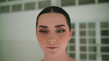 Portrait of a young woman with a serious expression, indoors with soft lighting and a blurred background. video