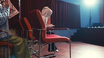 a woman in a hoodie looks embarrassed and falls down in the middle of a performance full of audience in a theater video