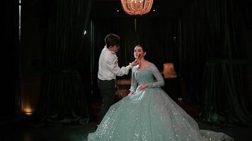 Elegant couple dancing in a dimly lit room with a chandelier, man leading the woman in a flowing dress. video