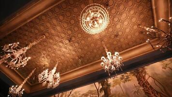 Elegant chandeliers hanging from an ornate ceiling with intricate patterns, providing a luxurious interior atmosphere. video