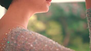 Elegant woman in a sequined dress, close-up on shoulder and hand, with a soft-focus background. video