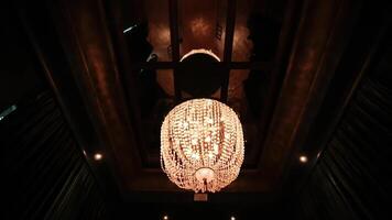 Elegant chandelier with warm lighting hanging from a dark ceiling, creating a cozy and luxurious ambiance. video