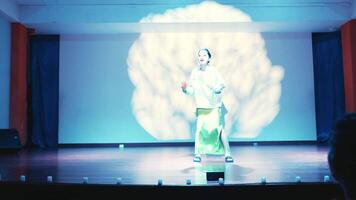 Performer on stage with dramatic lighting and brain projection in the background, depicting a conceptual performance. video