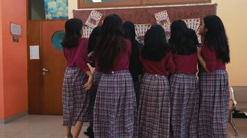 gruppo di studentesse nel uniformi in piedi insieme, visto a partire dal dietro, nel un' aula ambientazione. video