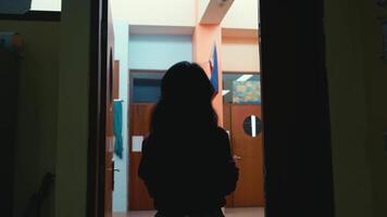 Silhouette of a person standing in a doorway with ambient indoor lighting. video