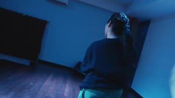 Dynamic image of a person dancing in a dimly lit room with blue lighting, capturing movement and energy. video