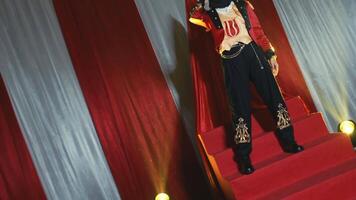 Confident young woman in a hijab and stylish jacket posing with attitude against a red curtain backdrop. video