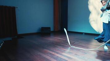 Stylish person dancing in a room with blue walls and a warm spotlight casting dynamic shadows. video