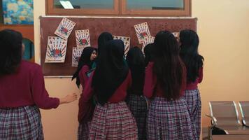 Group of students in traditional skirts looking at bulletin board in a classroom setting. video