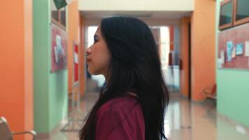 lato profilo di un' riflessivo donna a piedi nel un' colorato corridoio. video