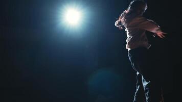 Silhouette of a person under a spotlight on a dark stage, suggesting a performance or presentation. video