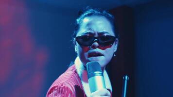 Female performer singing passionately into a microphone with vibrant blue stage lighting. video