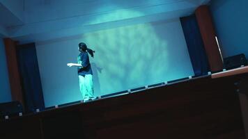performer Aan stadium met dramatisch blauw verlichting en abstract achtergrond projectie. video