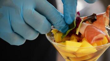 händer av professionell kock dekorera kopp mango frukt och skinka med örter deta video