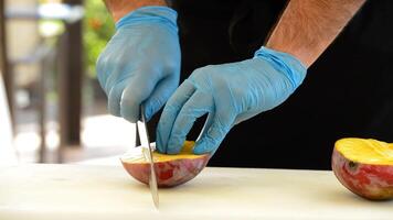 händer av kock eller professionell kock skärande en mango in i skivor video