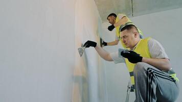 There are two masters who are working on the repair work in the apartment. Specialists are painters and plasterers who are plastering the walls in the apartment video