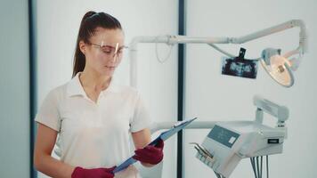 portrait de une femelle médecin et futur dentiste. caucasien femme avec une dossier de les documents dans sa mains dans le dentiste s bureau. video