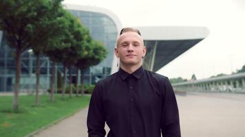 Portrait of a man on the background of modern buildings who slowly walks to the camera and smiles. video