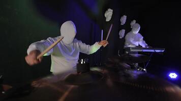 Illuminated Drummer Performance, A drummer with a hood over his face plays the rhythm on the drums video