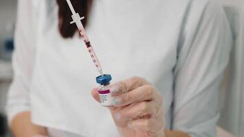 Nurse draws the vaccine into the syringe and prepares for the vaccination. A young nurse in a medical institution is vaccinated against coronavirus, influenza, and other diseases. video