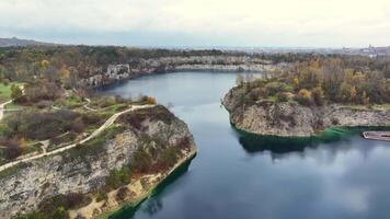 Autumn at Zakrzowek Quarry in Krakow, Aerial view of the serene Zakrzowek Quarry surrounded by autumn-colored trees with the Krakow skyline in the distance. video