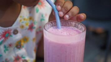 kind slokjes Aan een magenta guava sap met een drinken rietje video