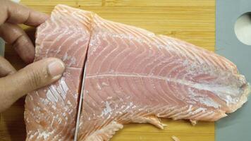 using knife slicing a fresh fish on wooden chopping board . video