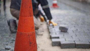 ein Arbeiter Verlegung Beton Ziegel auf jeder andere zum Gebäude ein Neu Bürgersteig video