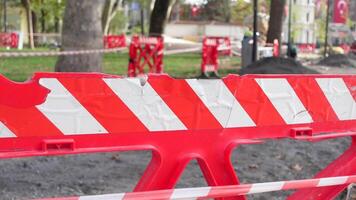 Warning sign of repair work put near striped red and white tape hanging on sticks. video