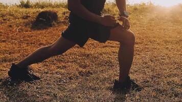 Attractive young man stretching in the park before running at the sunset focus on shoes video