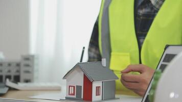 architetto e ingegneri con bozza Piano di edificio e tavoletta parlando su costruzione luogo. costruzione manager e ingegnere Lavorando su edificio luogo. video