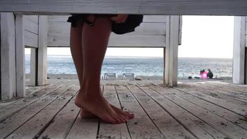 Woman in the changing, dressing room on the beach, at sunset on the seashore. The girl changes clothes, throwing up a swimsuit, then leaves the locker room in a pink dress. Close up, slow motion video