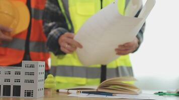 arquitecto y ingenieros con sequía plan de edificio y tableta hablando en construyendo sitio. construcción gerente y ingeniero trabajando en edificio sitio. video