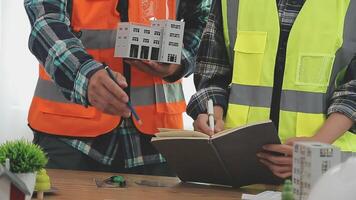 architector en ingenieurs met droogte plan van gebouw en tablet pratend Aan construeren plaats. bouw manager en ingenieur werken Aan gebouw plaats. video