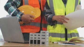 arquitecto y ingenieros con sequía plan de edificio y tableta hablando en construyendo sitio. construcción gerente y ingeniero trabajando en edificio sitio. video