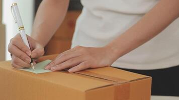 joven y atractiva mujer asiática propietaria de un negocio de inicio mira el trabajo de la cámara feliz con la caja en casa prepara la entrega de paquetes en la cadena de suministro de pymes, adquisiciones, omnicanal o concepto de cuarentena de coronavirus. video