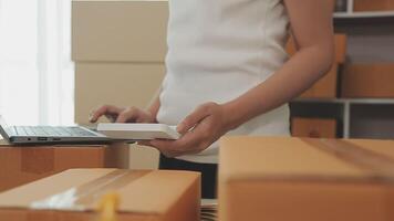 joven y atractiva mujer asiática propietaria de un negocio de inicio mira el trabajo de la cámara feliz con la caja en casa prepara la entrega de paquetes en la cadena de suministro de pymes, adquisiciones, omnicanal o concepto de cuarentena de coronavirus. video