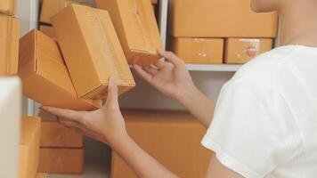 joven y atractiva mujer asiática propietaria de un negocio de inicio mira el trabajo de la cámara feliz con la caja en casa prepara la entrega de paquetes en la cadena de suministro de pymes, adquisiciones, omnicanal o concepto de cuarentena de coronavirus. video