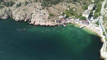 Aerial drone view on colorful kayaks grouped at a dock in sea bay. Group of happy kayakers are walking or training with instructor at sea bay. Active sea vacations concept video