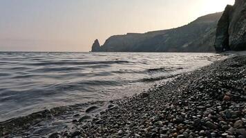 Meer Strand Horizont. Meer Wellen mit weich, schaumig Wasser Waschen mehrfarbig Kieselsteine auf ein Strand während Sonnenuntergang. niemand. Urlaub Erholung Konzept. abstrakt nautisch Sommer- Ozean Sonnenuntergang Natur schleppend Bewegung video