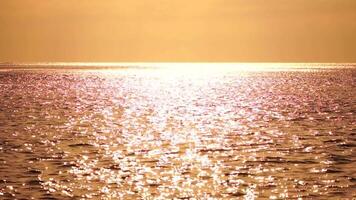 resumen mar verano Oceano puesta de sol naturaleza antecedentes. sonido de pequeño olas en dorado agua superficie en movimiento difuminar con dorado bokeh luces desde Dom. día festivo, vacaciones y recreativo concepto. video