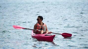 mar mujer kayac. contento mujer en vida chaqueta remar el kayac en mar. hembra es disfrutando su verano vacaciones a playa. mujer explorador calma mar por canoa en fiesta vacaciones fin de semana. video
