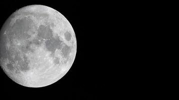 een gloeiend reusachtig vol maan gezien van aarde door de atmosfeer tegen een sterrenhemel nacht lucht. een groot vol maan beweegt aan de overkant de lucht, de maan in beweging van de bodem links kader naar de top Rechtsaf. video