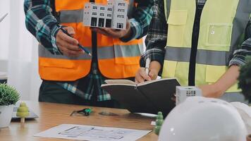 arquiteto e engenheiros com esboço, projeto plano do construção e tábua falando em construindo local. construção Gerente e engenheiro trabalhando em construção local. video