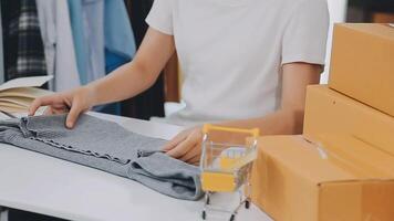 joven y atractiva mujer asiática propietaria de un negocio de inicio mira el trabajo de la cámara feliz con la caja en casa prepara la entrega de paquetes en la cadena de suministro de pymes, adquisiciones, omnicanal o concepto de cuarentena de coronavirus. video