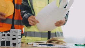 arquitecto y ingenieros con sequía plan de edificio y tableta hablando en construyendo sitio. construcción gerente y ingeniero trabajando en edificio sitio. video