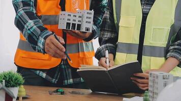 arquitecto y ingenieros con sequía plan de edificio y tableta hablando en construyendo sitio. construcción gerente y ingeniero trabajando en edificio sitio. video