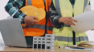 architector en ingenieurs met droogte plan van gebouw en tablet pratend Aan construeren plaats. bouw manager en ingenieur werken Aan gebouw plaats. video