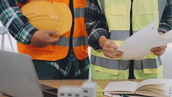 architector en ingenieurs met droogte plan van gebouw en tablet pratend Aan construeren plaats. bouw manager en ingenieur werken Aan gebouw plaats. video