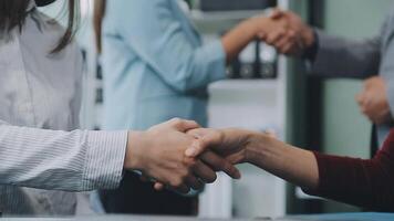 Young business people shaking hands in the office. Finishing successful meeting. Three persons. Wide screen panoramic video